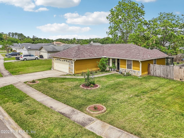 ranch-style home with concrete driveway, stone siding, a front yard, an attached garage, and fence