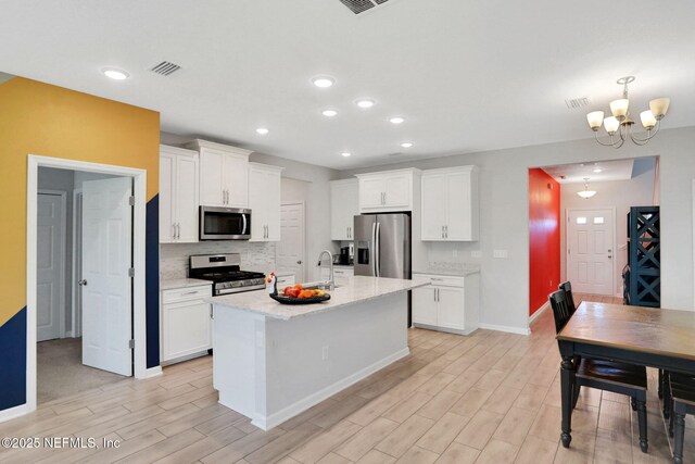 383 Narrowleaf Dr, Saint Johns, FL 32259 - kitchen with a notable chandelier, white cabinetry, light wood-style floors, and appliances with stainless steel finishes