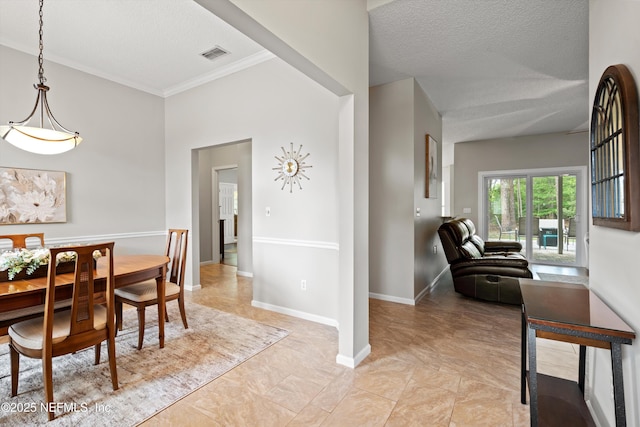dining room with baseboards, visible vents, ornamental molding, and a textured ceiling