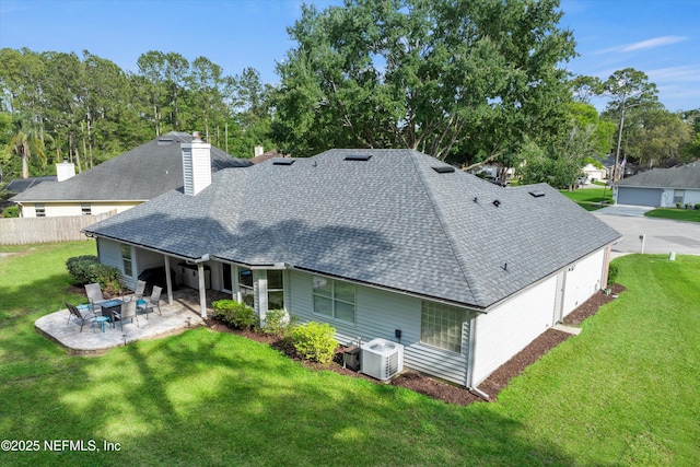 back of property with a patio, a shingled roof, and a yard