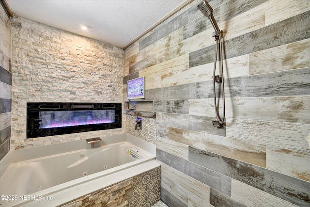 bathroom featuring a glass covered fireplace, a jetted tub, and a tile shower