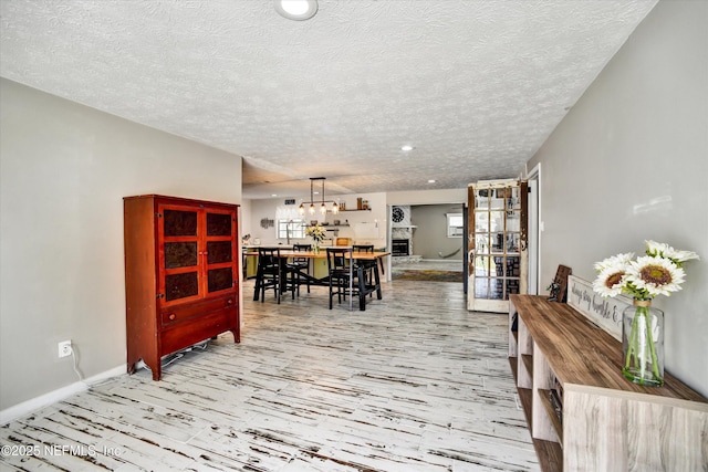 dining room with recessed lighting, a textured ceiling, baseboards, and light wood finished floors