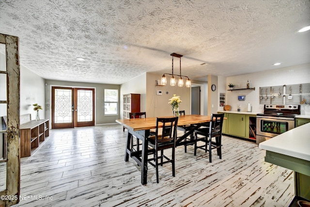 dining space with french doors, a textured ceiling, light wood-type flooring, baseboards, and recessed lighting