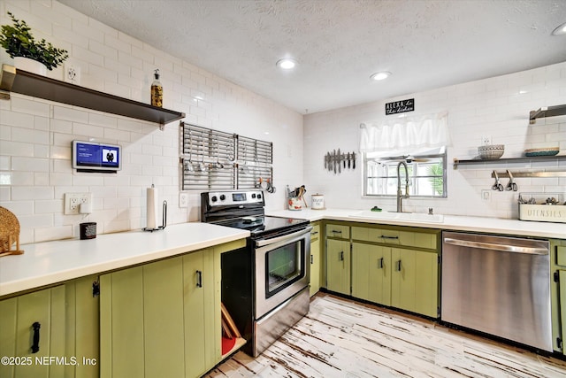 kitchen with a sink, open shelves, green cabinetry, and appliances with stainless steel finishes