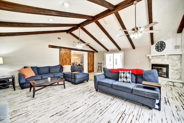 living area with ceiling fan, a stone fireplace, visible vents, wood finished floors, and lofted ceiling with beams