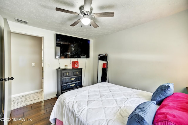 bedroom featuring wood finished floors, baseboards, a textured ceiling, and visible vents