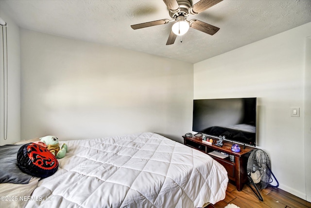 bedroom featuring a textured ceiling, ceiling fan, and wood finished floors