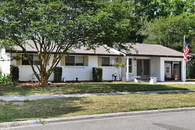 single story home with french doors, a shingled roof, a front yard, and brick siding