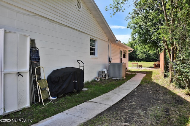 view of side of home featuring central AC unit and a yard
