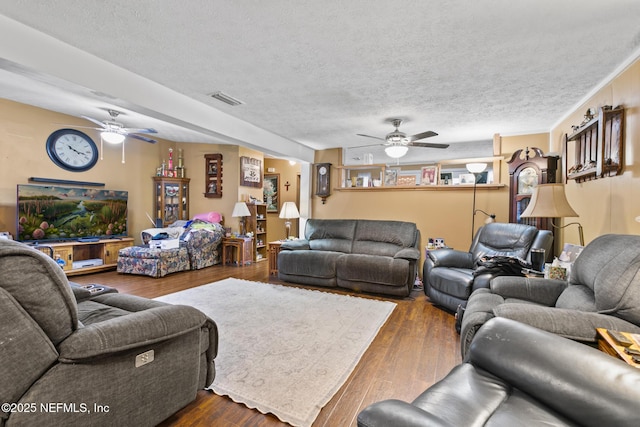 living area with a ceiling fan, visible vents, a textured ceiling, and dark wood-style flooring