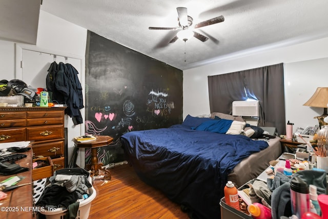 bedroom featuring wood finished floors, a textured ceiling, a ceiling fan, and cooling unit