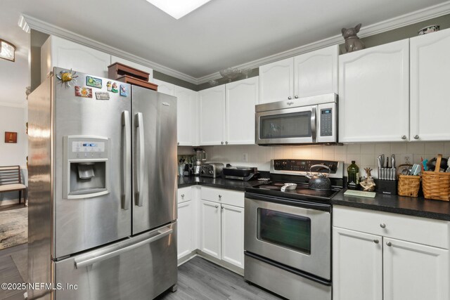 30936 Paradise Commons Unit 221, Fernandina Beach, FL 32034 - kitchen with white cabinets, stainless steel appliances, light wood-type flooring, and ornamental molding
