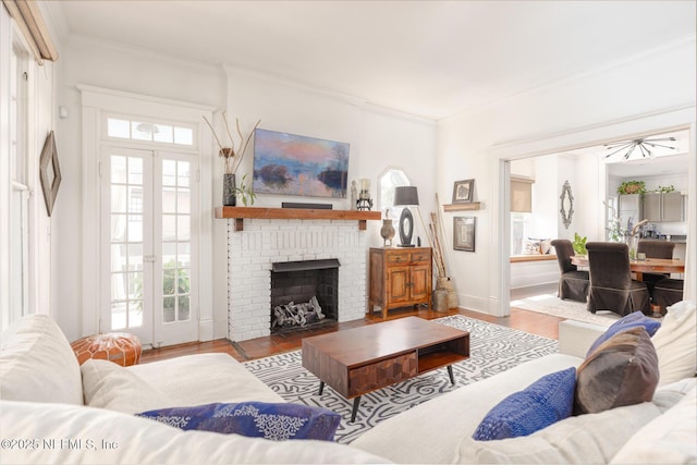 living room featuring crown molding, a fireplace, wood finished floors, and a healthy amount of sunlight