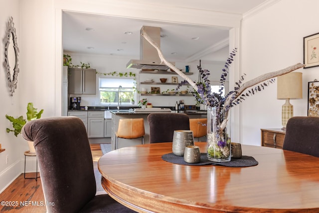 dining room featuring light wood-style floors, baseboards, and crown molding