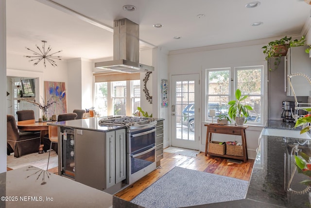kitchen with crown molding, range with two ovens, plenty of natural light, and island exhaust hood