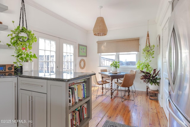 kitchen featuring open shelves, freestanding refrigerator, dark stone counters, ornamental molding, and light wood-style flooring