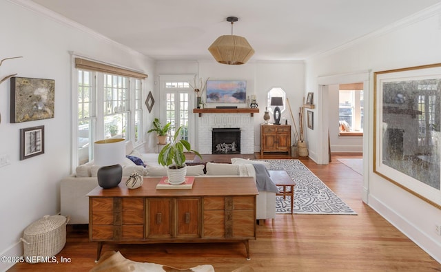 living area featuring baseboards, ornamental molding, a brick fireplace, and wood finished floors