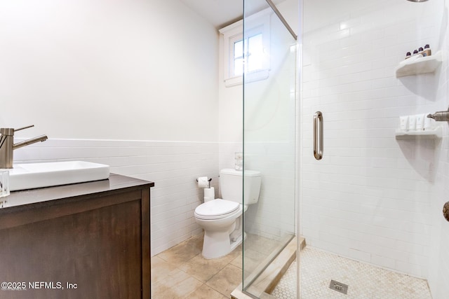 full bath featuring wainscoting, toilet, a shower stall, and tile patterned flooring
