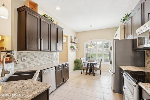 716 Hazelmoor Ln, Ponte Vedra, FL 32081 - kitchen with light stone countertops, dark brown cabinetry, a sink, stainless steel appliances, and baseboards