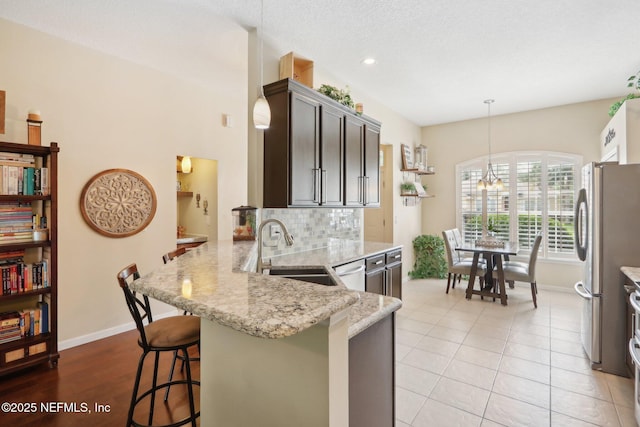 716 Hazelmoor Ln, Ponte Vedra, FL 32081 - kitchen featuring appliances with stainless steel finishes, light stone countertops, a sink, baseboards, and a peninsula