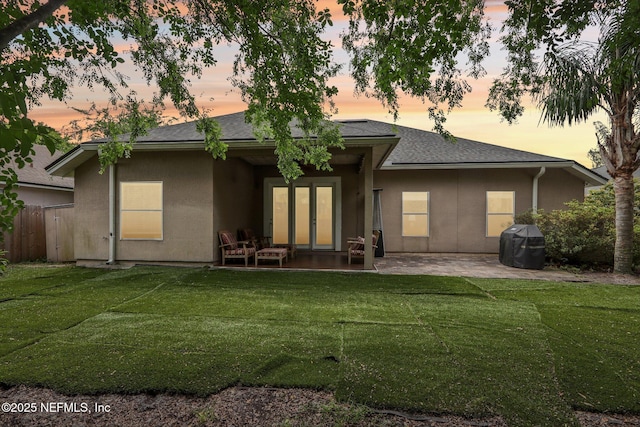 716 Hazelmoor Ln, Ponte Vedra, FL 32081 - back of property at dusk featuring a lawn, a patio area, stucco siding, and french doors