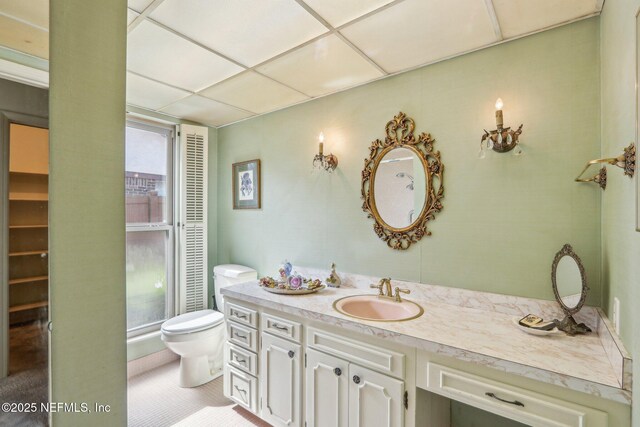 bathroom featuring tile patterned floors, toilet, vanity, and a paneled ceiling