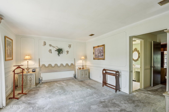 bedroom with ornamental molding, visible vents, a decorative wall, and carpet floors