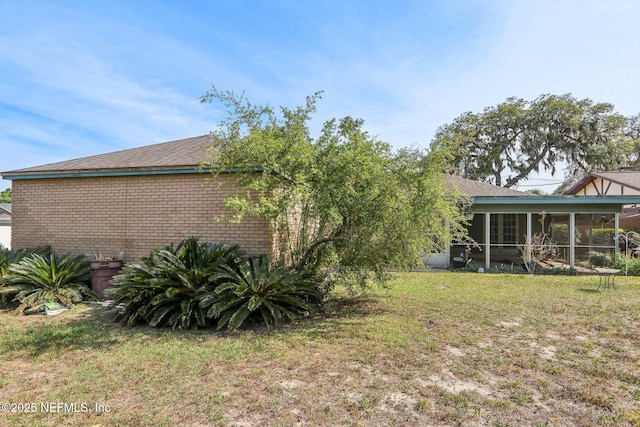back of property with a lawn and a sunroom