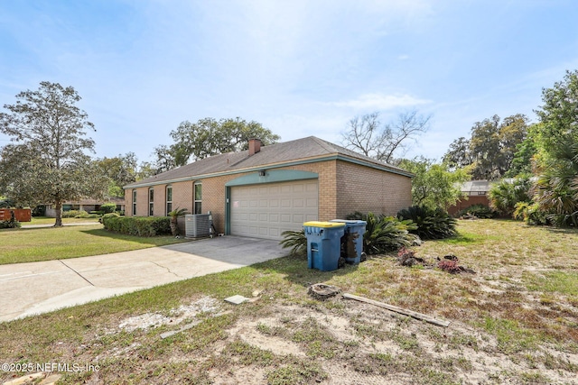 view of home's exterior with a chimney, brick siding, a garage, concrete driveway, and a lawn