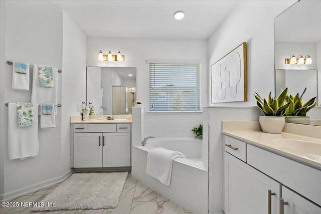 full bath with a shower stall, marble finish floor, a sink, two vanities, and a garden tub