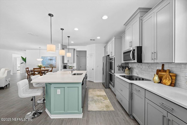 kitchen featuring tasteful backsplash, a sink, light wood-style flooring, light countertops, and appliances with stainless steel finishes