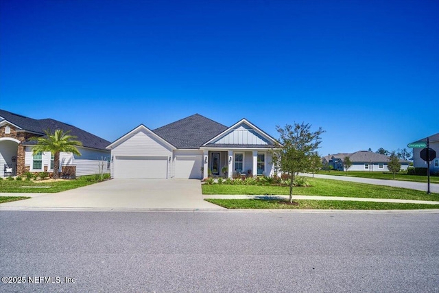view of front of home with driveway, a front yard, board and batten siding, and a garage