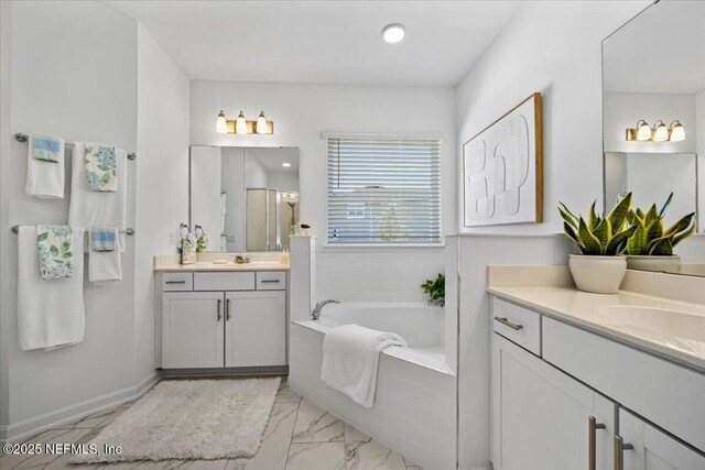 bathroom with marble finish floor, a sink, a bath, two vanities, and a stall shower