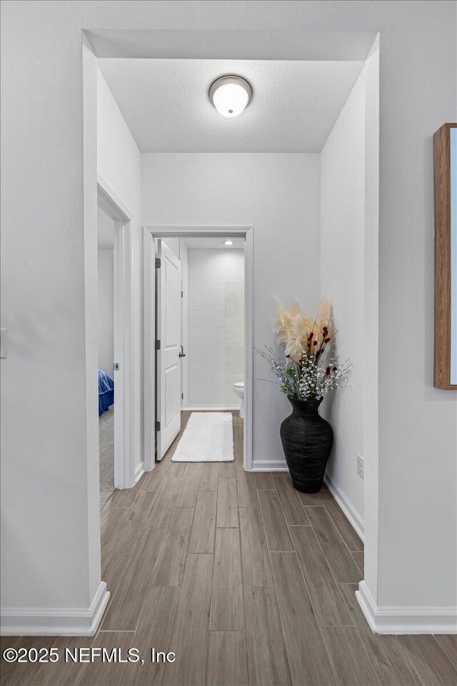 hallway with baseboards and wood finished floors