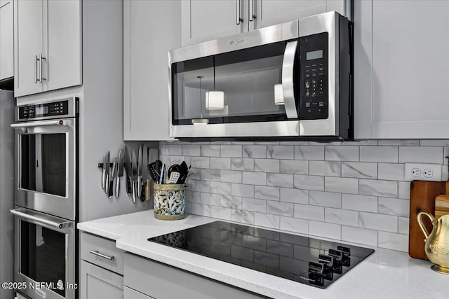 kitchen featuring light stone counters, decorative backsplash, and stainless steel appliances