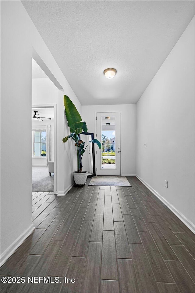 foyer entrance with a textured ceiling, wood finish floors, a ceiling fan, and baseboards