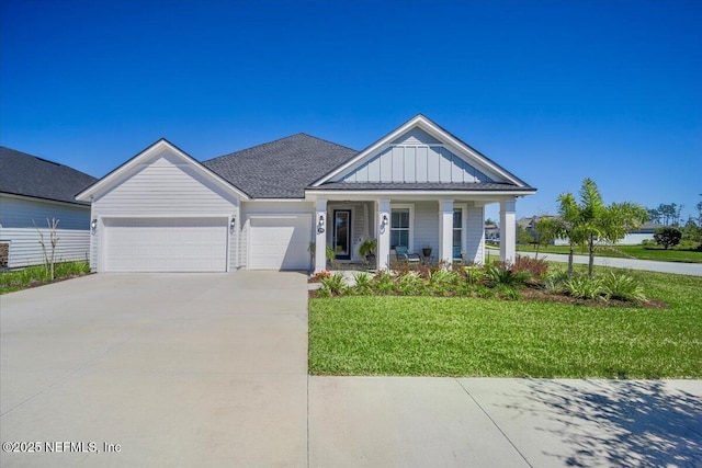 view of front of property with a front lawn, an attached garage, board and batten siding, driveway, and a porch