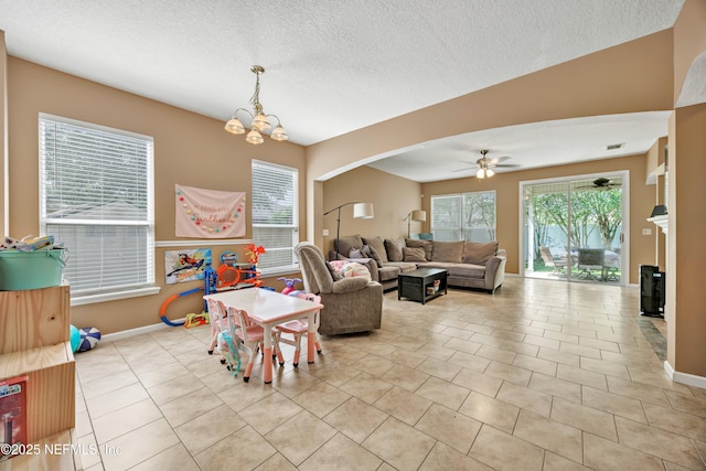 living room with light tile patterned floors, arched walkways, baseboards, a textured ceiling, and ceiling fan with notable chandelier