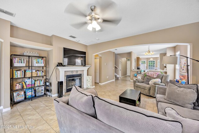 living area featuring baseboards, visible vents, arched walkways, and ceiling fan with notable chandelier