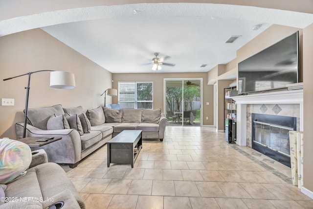living room with a fireplace, light tile patterned floors, visible vents, and ceiling fan