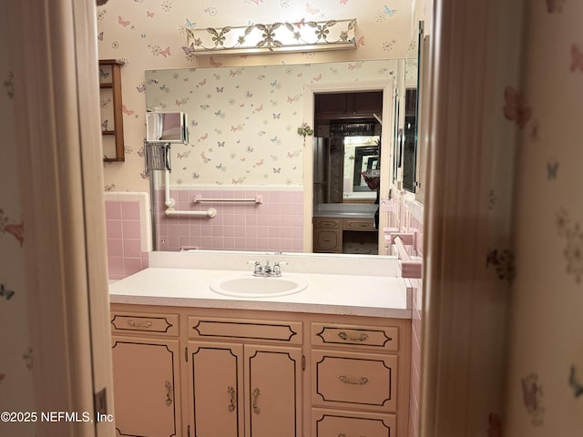 3715 Rustic Ln, Jacksonville, FL 32217 - bathroom with wallpapered walls, a wainscoted wall, vanity, and tile walls