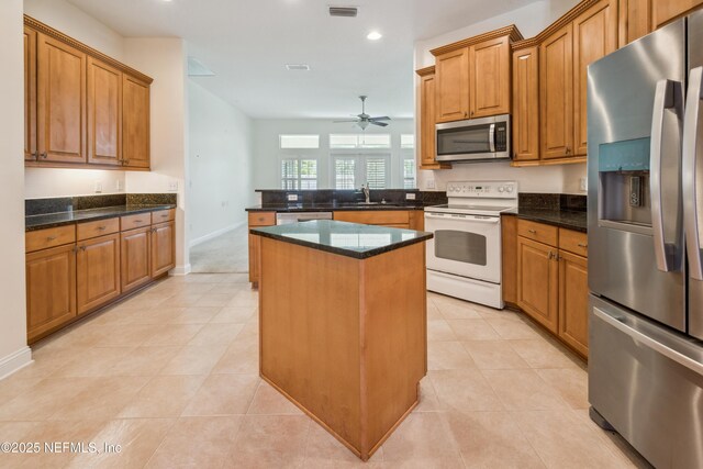 3099 Five Oaks Ln, Green Cove Springs, FL 32043 - kitchen with appliances with stainless steel finishes, a ceiling fan, a peninsula, a kitchen island, and brown cabinetry