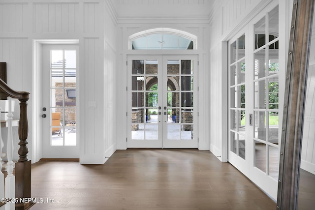 entryway with dark wood-style flooring, ornamental molding, french doors, and a decorative wall