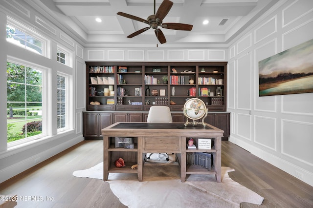 office space with coffered ceiling, a healthy amount of sunlight, and a decorative wall