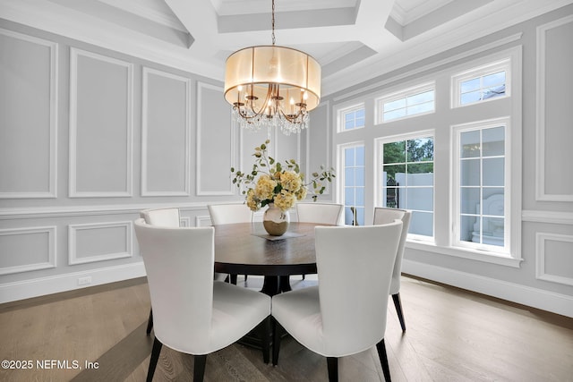 dining room featuring a notable chandelier, coffered ceiling, and a decorative wall