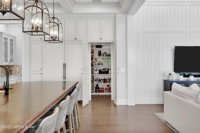 interior space featuring an inviting chandelier, crown molding, wood finished floors, beamed ceiling, and baseboards
