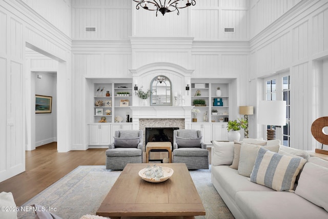 living room featuring a high ceiling, an inviting chandelier, wood finished floors, and a fireplace