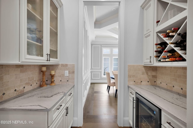 bar featuring decorative backsplash, wood finished floors, wine cooler, ornamental molding, and a bar