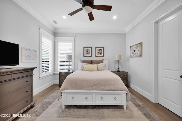 bedroom with crown molding, baseboards, visible vents, and wood finished floors