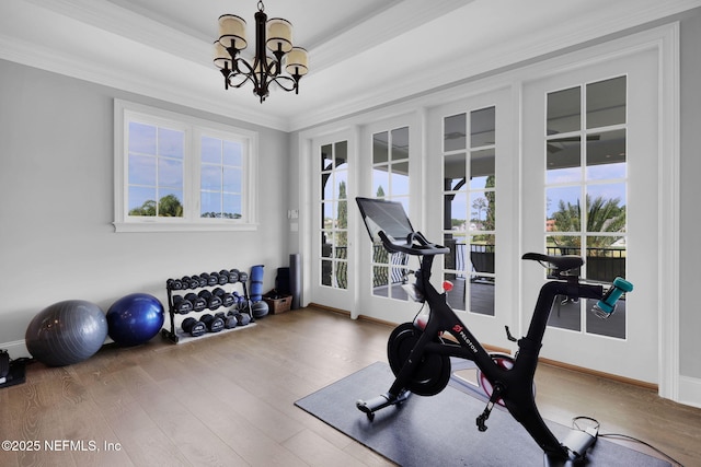 exercise room with an inviting chandelier, ornamental molding, and wood finished floors